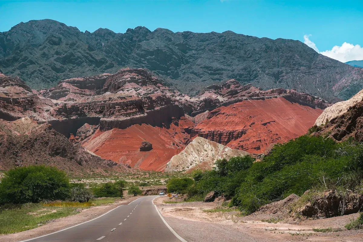 A road leading to a red-orange mountain