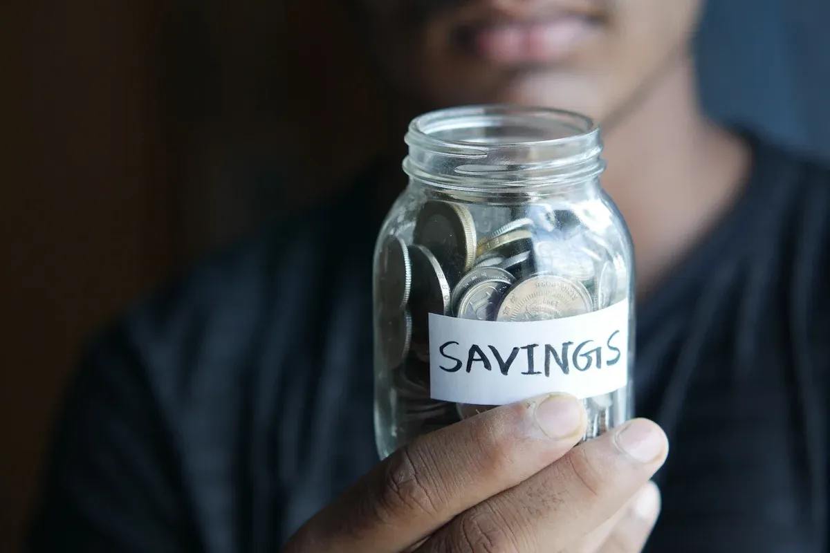 A man holding a jar of savings