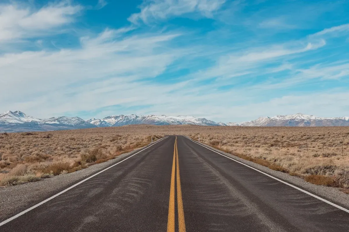 A road through the desert towards snow-capped mountains